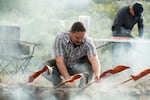 Richard Whitney, a wildlife manager at Colville Tribes Fish and Wildlife, prepares salmon immediately after an early morning salmon ceremony. The salmon is skewered and then placed over a fire, to be eaten for lunch just a few hours later.