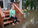 Rachel Morsching sits Tuesday on the flooded porch of her father Dean Roemhildt's home in Waterville., Minn. Waters from the nearby Tetonka and Sakatah lakes have encroached on the town amid recent heavy rains.