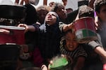 Palestinians struggle to get donated food at a community kitchen in Khan Younis, Gaza Strip, Monday.