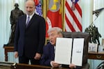 President Trump holds up an executive order to limit mail-in voting as Commerce Secretary Howard Lutnick looks on in the White House’s Oval Office in March.