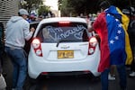 People unload donated goods from a car marked "For Venezuela" as humanitarian aid to be sent to Venezuela following deadly earthquakes, in Bogota on June 26, 2026.