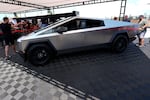 Visitors look over a 2024 Cybertruck in the Tesla display at the Electrify Expo, Sunday, July 14, 2024, in north Denver. The exposition was making its first stop in Denver as part of a countrywide effort to showcase the latest in a wide array of electric brands ranging from cars and trucks to bicycles and even skateboards. (AP Photo/David Zalubowski)