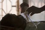 A person's hand adjusts the oxygen mask of a tuberculosis patient at a hospital.