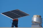 A worker carries a solar panel on the roof of the Alta Sea building, an urban, ocean-based research and blue technology innovation campus, at Berth 58 in the Port of Los Angeles on Thursday, Sept. 4, 2025.