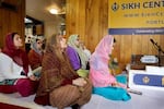 Women pray inside the gurdwara, which is located inside a single-family home.
