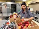 Packed with Pride volunteer Julie Merkl sorts a box of apples at Christ the King Lutheran Church in Tigard, Ore.. on Nov. 6, 2025.