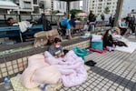 Residents rest nearby in the aftermath of a fire which broke out Wednesday at Wang Fuk Court, a residential estate in the Tai Po district of Hong Kong's New Territories, Thursday, Nov. 27, 2025.