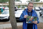 FILE - In this March 12, 2020, file photo, Scott Sedlacek poses while holding a photo of his father, Chuck, outside Life Care Center in Kirkland, Wash., near Seattle. Sedlacek battled having COVID-19 while his father also fought the virus and was under care in the facility. Both have since recovered. Hearing of President Donald Trump's advice-by-Tweet on Monday, Oct. 5, 2020, not to fear the disease, as well as Trump's reckless insistence on riding in a motorcade outside Walter Reed Medical Center and on returning to the White House while still infectious, enraged him. (AP Photo/Ted S. Warren, File)