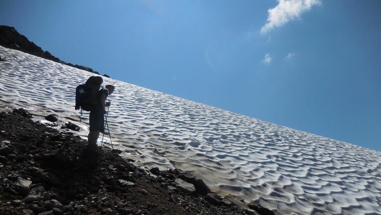 Backpacker Alex Ostrom of Seattle prepares to cross a snowfield on the Lily Basin Trail in the Goat Rocks Wilderness.