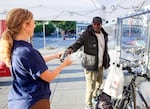Blanchet House staff member Julie Showers, left, hands a bottle of water to Roy Medals, during  the heat wave in Portland, Aug. 22, 2025. Medals is currently unhoused.