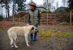 A man standing in his yard next to a large white dog.