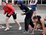 Westview junior Asha Muse (center, in blue) gets ready to run the 100-meter event at Southridge High School on March 20, 2024, which falls during Ramadan.  She is one of many students on her track team fasting for the holy month while doing athletic training. She also cooks for her large family's Iftar meal, which usually includes chicken sambusa.