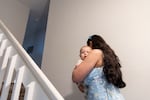 Susan Kufdakis walks up a staircase carrying her son.