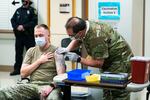 Staff Sgt. Travis Snyder, left, receives the first dose of the Pfizer vaccine for COVID-19 given at Madigan Army Medical Center at Joint Base Lewis-McChord, Wednesday, Dec. 16, 2020, in Washington state, south of Seattle. Nurse Jose Picart, right, administered the shot. Vaccinations are scheduled to continue in the coming weeks for front-line medical workers and and others in high-priority positions at the base.