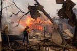 Firefighters battle the Palisades Fire as it burns a structure in the Pacific Palisades neighborhood.