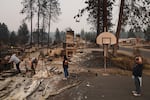 From left, homeowner Al Acosta, his son Louis Acosta, daughter Renee Stewart and son-in-law Jamie Stewart look through the remains of Al's home after a wildfire hit the northern part of Spokane, Wash., Monday, Aug. 3, 2026.