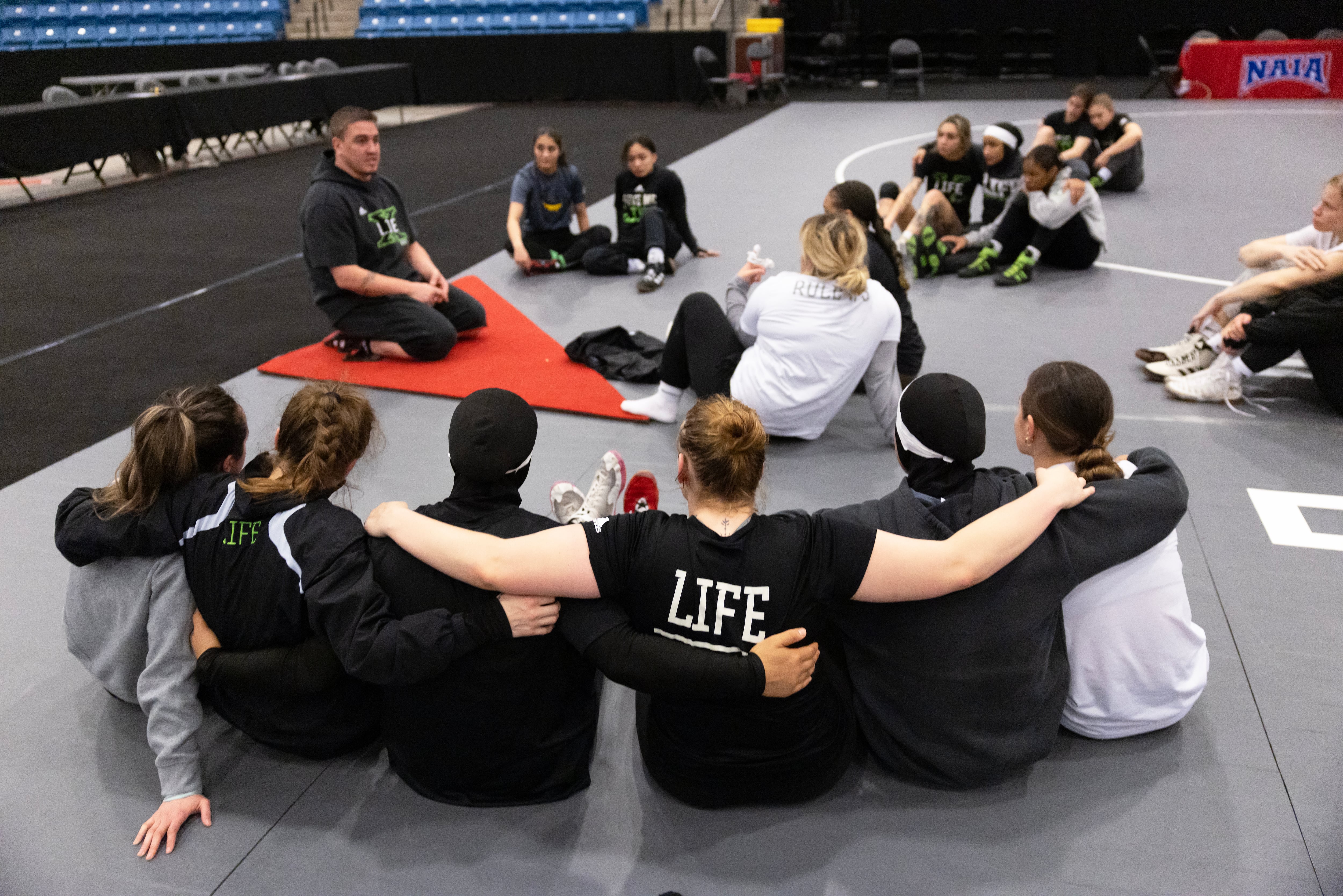 Life University associate head wrestling coach Christian Flavin, who is married to head coach Ashley Flavin, does an emotional check-in with his team on the eve of the 2025 NAIA Women's Wrestling National Championship.