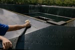 A visitor leaves a white rose at the 9/11 memorial fountains in New York City on Sept. 2.