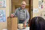 A neighborhood resident collects a turkey and a bag of food for the holiday from the ABCD Allston/Brighton Neighborhood Opportunity Center in Boston.