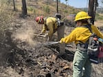 Firefighters use hand tools and cool off hot spot areas while battling the Durkee Fire, in this handout image posted on Aug. 4, 2024.