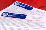 A document with U.S. government seals on it reads "BULLETIN" in large font, and then "summary of the terrorism threat to the U.S. homeland" in smaller red font. Additional writing is too small to read.