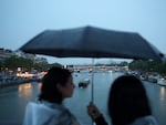 Athlete boats travel along the River Seine as spectators shelter from the rain during the opening ceremony of the Olympic Games Paris 2024 on July 26.