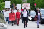 People hold up signs supporting abortion access as they march on a sidewalk