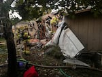 Firefighters from Tualatin Valley Fire & Rescue stand by to extinguish any fire that erupts from a small plane that had crashed Tuesday, Oct. 3, 2023, into a home in Newberg, Oregon. The plane never caught fire, but two people aboard the craft died and another was injured.