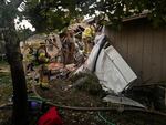 Firefighters from Tualatin Valley Fire & Rescue stand by to extinguish any fire that erupts from a small plane that had crashed Tuesday, Oct. 3, 2023, into a home in Newberg, Oregon. The plane never caught fire, but two people aboard the craft died and another was injured.