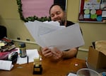 Chris Mathews, English teacher at David Douglas High School, holds up a stack of papers at his desk on Jan. 22, 2025. Mathews said attending a great public elementary school growing up factored into his wanting to be a teacher.
