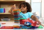 Winnie VanDusen, 3, plays with blocks at Bumble Art Studio day care center in Astoria, Ore., in this Sept. 2, 2022 file photo. A recent study shows that more than 40% of parents said they or their partner had quit a job, not taken a job or “greatly changed” a job because of difficulty finding child care the previous year.