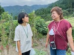 Satomi Oigawa (left) and village resident Tomiko Kanbe talk on a hillside outside the village center. Kanbe helps attract and mentor enterprising young people.