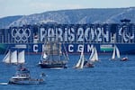 FILE - The Belem, the three-masted sailing ship bringing the Olympic flame from Greece, center, sails past a containership decorated with the Paris 2024 logo when approaching Marseille, southern France, May 8, 2024.