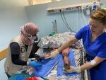 Burn nurse Monica Johnston on Thursday shows a local nurse a burn wound on 7-year-old Zain Abu Obeid, who was injured in a blast that killed his family. He died four days later.