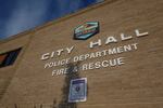 A brown brick building with the words "city hall" in all capital letters placed on it. The city of Ontario logo is above the city hall sign and a sign for the police department and fire & rescue are below it.