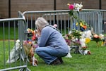 A visitor offers a tribute after leaving a bouquet of flowers at a makeshift memorial for victims of an attack outside of the Boulder County, Colo., courthouse as a light rain falls Tuesday, June 3, 2025, in Boulder, Colo. (AP Photo/David Zalubowski)