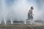 A child runs through a fountain that splashes water from every direction.