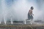 A child runs through a fountain that splashes water from every direction.