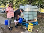 Teresa Thomas (left) and her son David Murray fill up plastic containers with gray water at the apartment complex in Asheville where she lives.