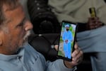 A Pakistani Mohammad Akram shows a picture of his son Abu Bakar, one of the victims of a migrant boat that capsized in West Africa's Atlantic coastline, on his cell phone at his home, in Jura village, in the Lalamusa district in Pakistan, on Friday.