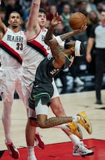 Minnesota Timberwolves guard Nickeil Alexander-Walker, right, shoots over Portland Trail Blazers center Donovan Clingan, center, and forward Toumani Camara during the second half of an NBA basketball game in Portland, Ore., Wednesday, Nov. 13, 2024.