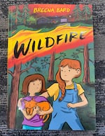 A book cover that two nervous-looking young girls in the woods holding a cat. The word "Wildfire" is emblazoned above their heads.