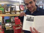 Nate Fasold at Powell's Books pointing to a photo of Elliott Smith. Fasold is on a mission to determine whether the guitar in the photo is the same guitar someone is offering to sell to his shop.