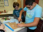 Seventh graders Michael Herrera and Nicolas Barbee cut foam for the model boat's hull.