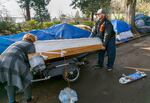 Merideth O'Neill, left, receives help from Tyler Hardy at the Laurelhurst Park encampment, Dec. 7, 2020. Last month, the city of Portland cleared 70-100 makeshift homes of people living near Laurelhurst Park last month. Hardy and O'Neill have returned, along with many others.