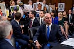 Then-Boeing CEO Dennis Muilenburg, center foreground, prepares to testify during an Oct. 29, 2019, hearing on Capitol Hill as family members hold up photographs of those killed in the Ethiopian Airlines Flight 302 and Lion Air Flight 610 crashes.