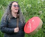 A Coquille Tribal member blesses salmon with a song while beating a hand drum.