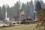 A burned car smolders in front of a burned out residential home in the Balboa neighborhood of Spokane, Wash., on August 2, 2026.