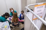 (Left to right) Nursing students Maya Hermens and Melissa Christensen administer a vaccine for Ava Schwartzkoph, 9, as her brother Flynn, 8, looks on at a pediatric COVID-19 vaccine clinic held at Clackamas Town Center, Nov. 10, 2021 in Happy Valley, OR. The clinic was offered by the Clackamas County’s Department of Public Health and offered Pfizer-BioNTech vaccines for children ages 5 through 11 years old.