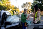 Volunteer Gabi Carter helps Nan Ahseln pack food in her car outside the Ecumenical Ministries of Oregon’s Northeast Emergency Food Program food bank in Portland, Ore., on Tuesday, Oct. 21, 2025.